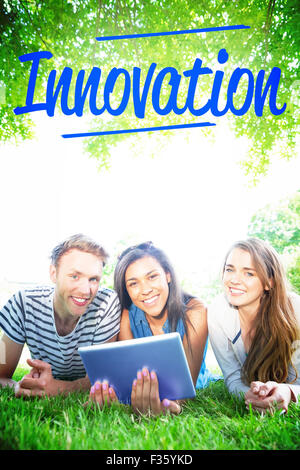 Innovation against happy students using tablet pc outside Stock Photo