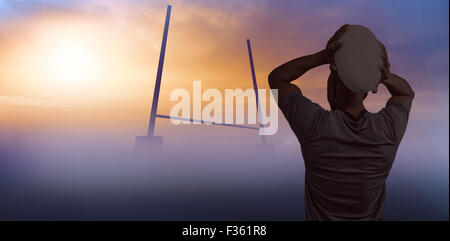 Composite image of rear view of sportsman throwing rugby ball Stock Photo