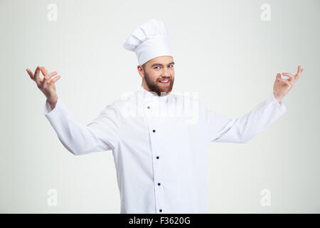 Portrait of a happy chef cook showing welcome gesture isolated on a white background