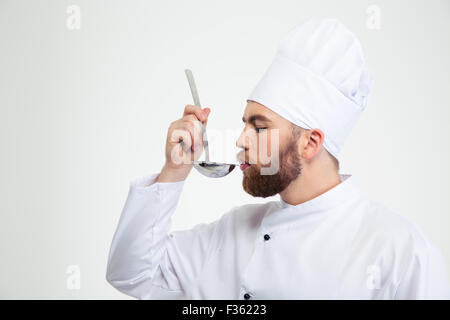 Portrait of a male chef cook holding a soup ladle and smelling it isolated on a white background