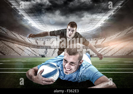 Composite image of confident rugby player lying in front with ball Stock Photo