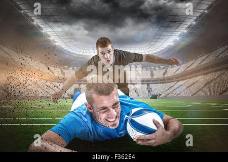 Composite image of confident rugby player lying in front with ball Stock Photo