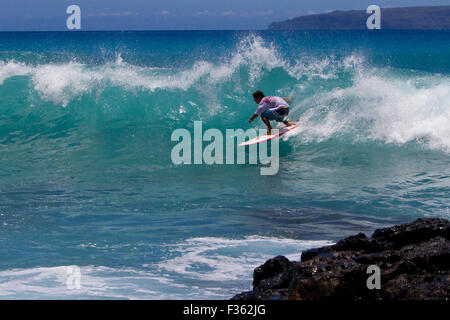 A surfer riding the waves at Kanahena Beach, Maui, Hawaii in July Stock Photo