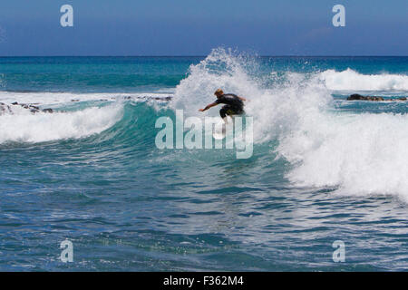 A surfer riding the waves at Kanahena Beach, Maui, Hawaii in July Stock Photo