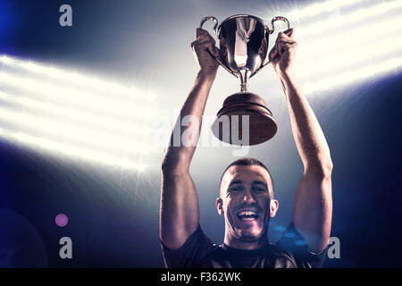 Composite image of portrait of successful rugby player holding trophy Stock Photo