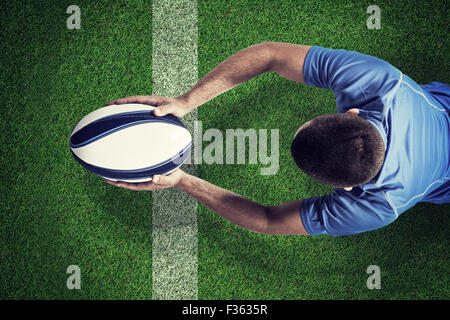 Composite image of rugby player lying in front with ball Stock Photo