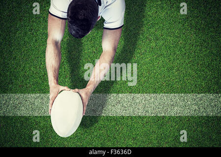 Composite image of high angle view of man holding rugby ball with both hands Stock Photo