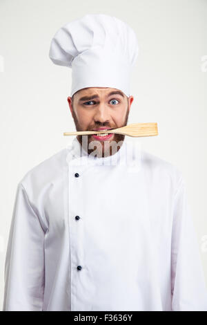 Portrait of a handsome male chef cook holding spoon in teeth isolated on a white background Stock Photo