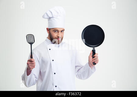 Portrait of a handsome male chef cook holding pan and spoon isolated on a white background Stock Photo