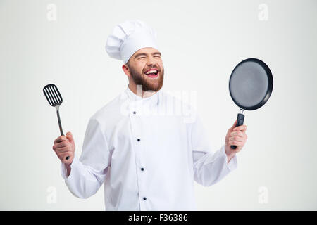 Portrait of a laughing male chef cook holding spoon and pan isolated on a white background Stock Photo