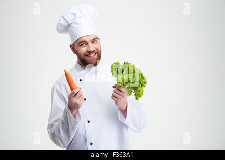 Portrait of a smiling chef cook holding salad and carrot isolated on a white background Stock Photo