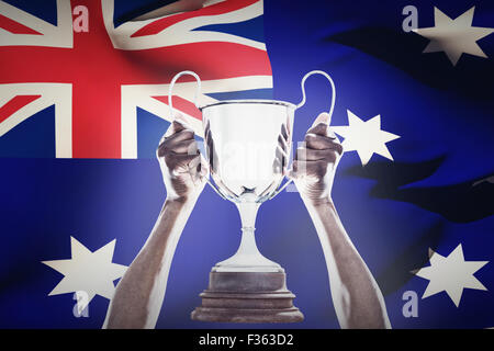 Composite image of cropped hand of athlete holding trophy Stock Photo