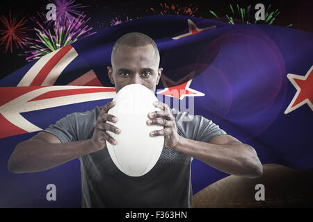Composite image of portrait of sportsman pressing rugby ball Stock Photo