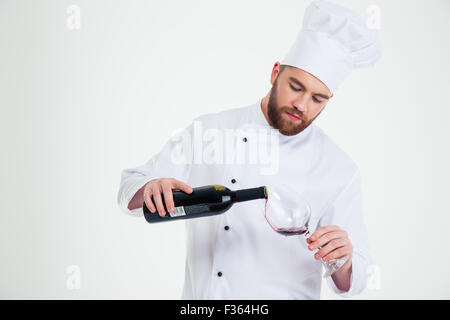 Portrait of a male chef cook pouring wine in wineglass isolated on a white background Stock Photo