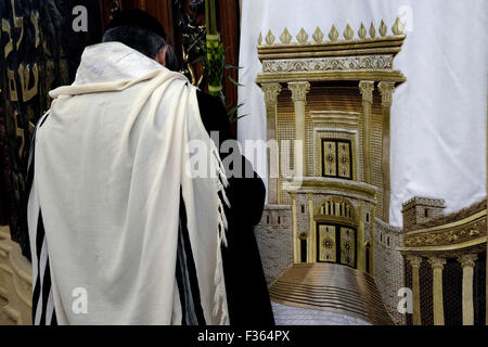 A Jewish worshiper praying next to a Torah Ark closet which contains the Jewish Torah scrolls decorated with a figure depicting the Biblical Jewish Temple inside the men's section of Wilson's Arch at the Western Wall compound in the old city. East Jerusalem, Israel Stock Photo