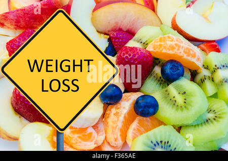 Yellow roadsign with message WEIGHT LOSS over background of healthy fresh fruits Stock Photo