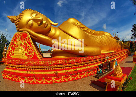 Giant gold reclining sleeping Buddha statue near Wat That Luang Temple, Vientiane, Laos Stock Photo
