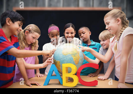 Composite image of cute pupils and teacher looking at globe in library Stock Photo