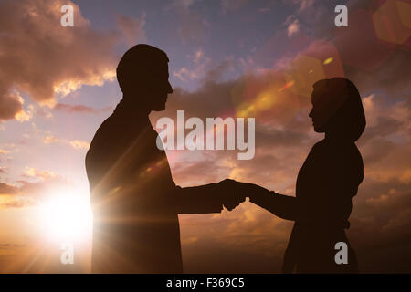 Composite image of silhouette of business people shaking hands Stock Photo