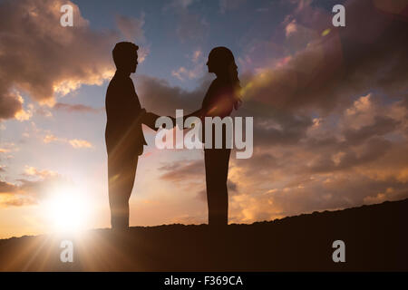 Composite image of silhouette of business people shaking hands Stock Photo