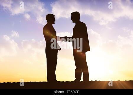 Composite image of silhouettes shaking hands Stock Photo