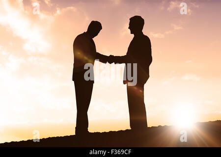 Composite image of silhouettes shaking hands Stock Photo