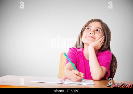 Composite image of cute pupil working at her desk Stock Photo