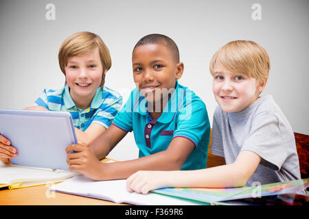 Composite image of cute pupils using tablet computer in library Stock Photo