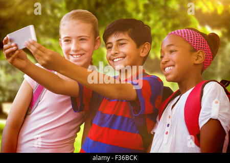 Composite image of happy kids taking selfie in school corridor Stock Photo