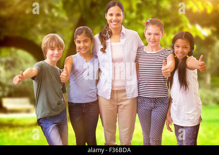 Composite image of cute pupils and teacher smiling at camera in computer class Stock Photo