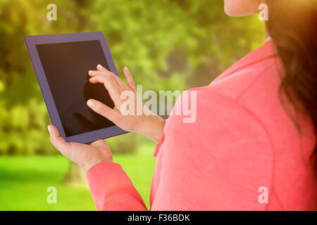 Composite image of elegant brunette using tablet Stock Photo