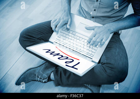 Team against young creative businessman working on laptop Stock Photo