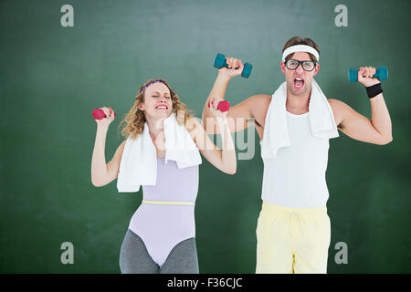 Composite image of geeky hipster couple lifting dumbbells in sportswear Stock Photo