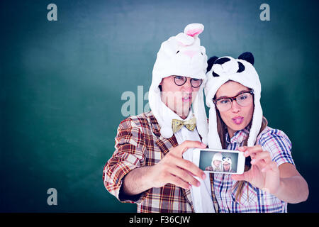 Composite image of geeky hipster couple taking selfie with smart phone Stock Photo