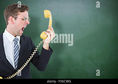 Composite image of geeky businessman shouting at telephone Stock Photo
