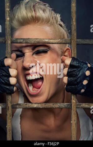 Punk girl screaming behind bars Stock Photo