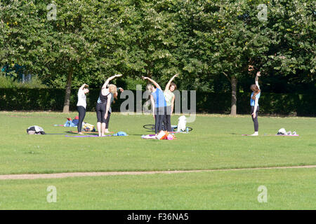 Outdoor yoga class with group of women stretching on warm summers day in Russell Park, Bedford, Bedfordshire, England Stock Photo