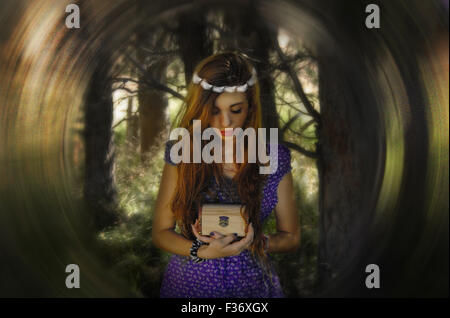 beautiful girl holding a box treasure with a crone in the head in the forest Stock Photo
