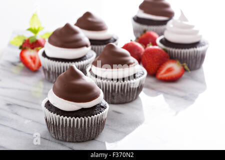 Chocolate meringue cupcakes with chocolate glaze and strawberries Stock Photo