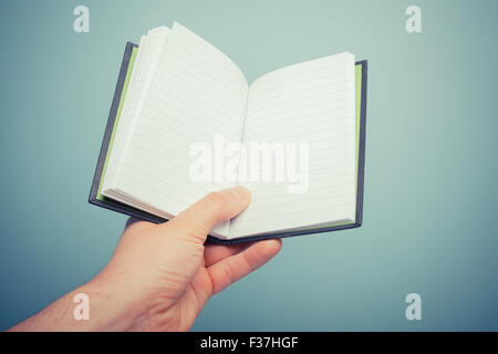 A hand is holding a small notebook Stock Photo