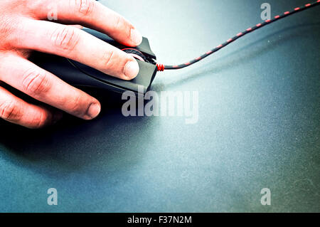 Male hand holding computer mouse on black surface. Computer technology conceptual image. Stock Photo