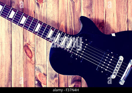 Guitar conceptual image. Picture of electric guitar lying on wooden background. Retro vintage instagram picture. Stock Photo