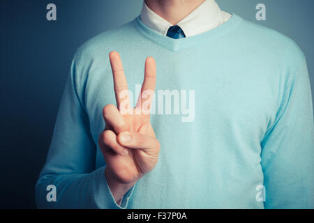 A young man is gesturing a peace sign Stock Photo