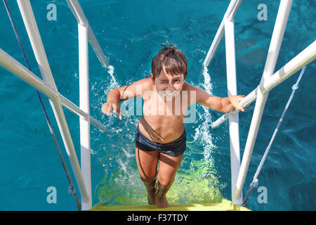 A young boy climbs the stairs from the sea Stock Photo