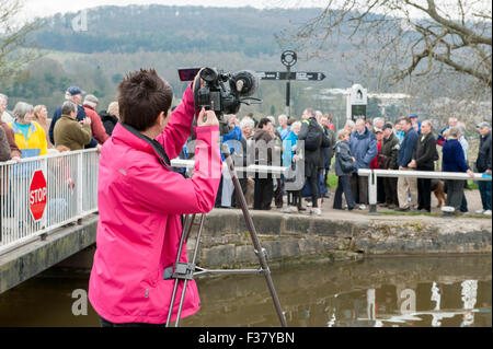 TV camera crew (female behind the lens) filming people at 2012 Sports Relief event - Bingley Five Rise Locks, Leeds-Liverpool Canal, England, GB, UK. Stock Photo