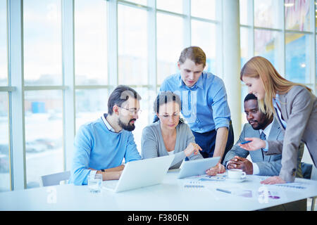 Group of employees consulting electronic data while making analysis Stock Photo