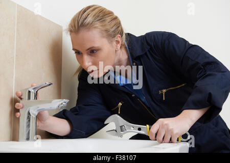 Female Plumber Working On Sink Using Wrench Stock Photo