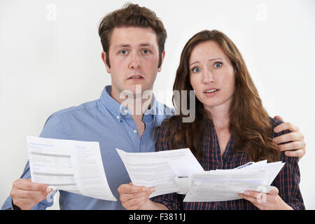 Studio Shot Of Worried Couple Looking At Bills Stock Photo