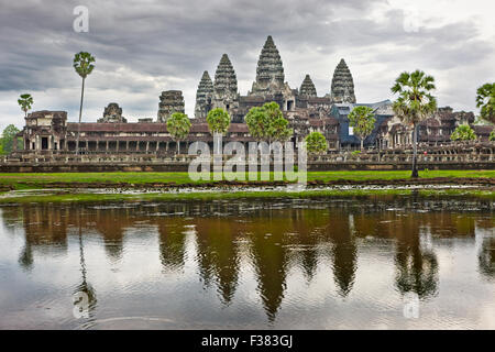 Iconic view of the Angkor Wat temple reflected in a nearby lake on a cloudy day. Angkor Archaeological Park, Siem Reap Province, Cambodia. Stock Photo