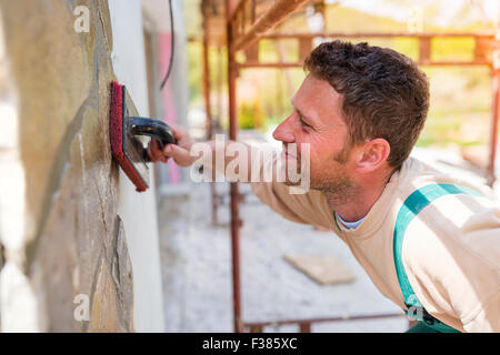 Man putting natural stones on a wall Stock Photo